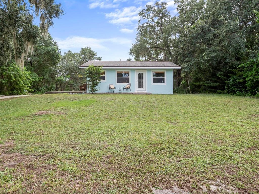 A light blue, single-story house sits in a large, grassy yard surrounded by mature trees — 4220 N OCEAN SHORE BOULEVARD, PALM COAST, FL