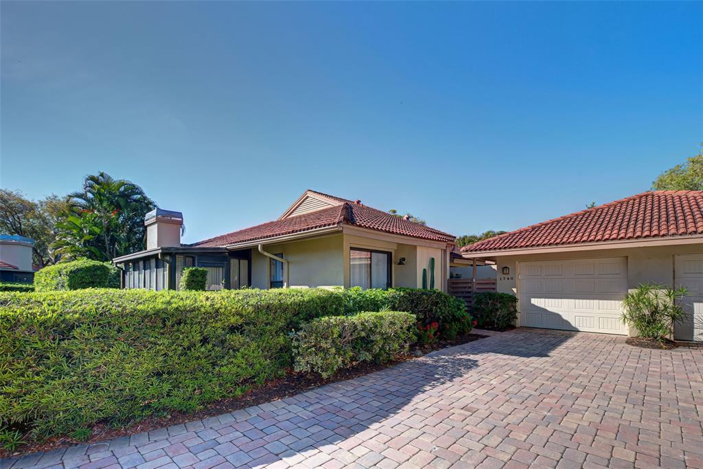 A single-story house with a tiled roof, a brick driveway, and a manicured hedge — 1740 LANDINGS BOULEVARD UNIT 39, SARASOTA, FL