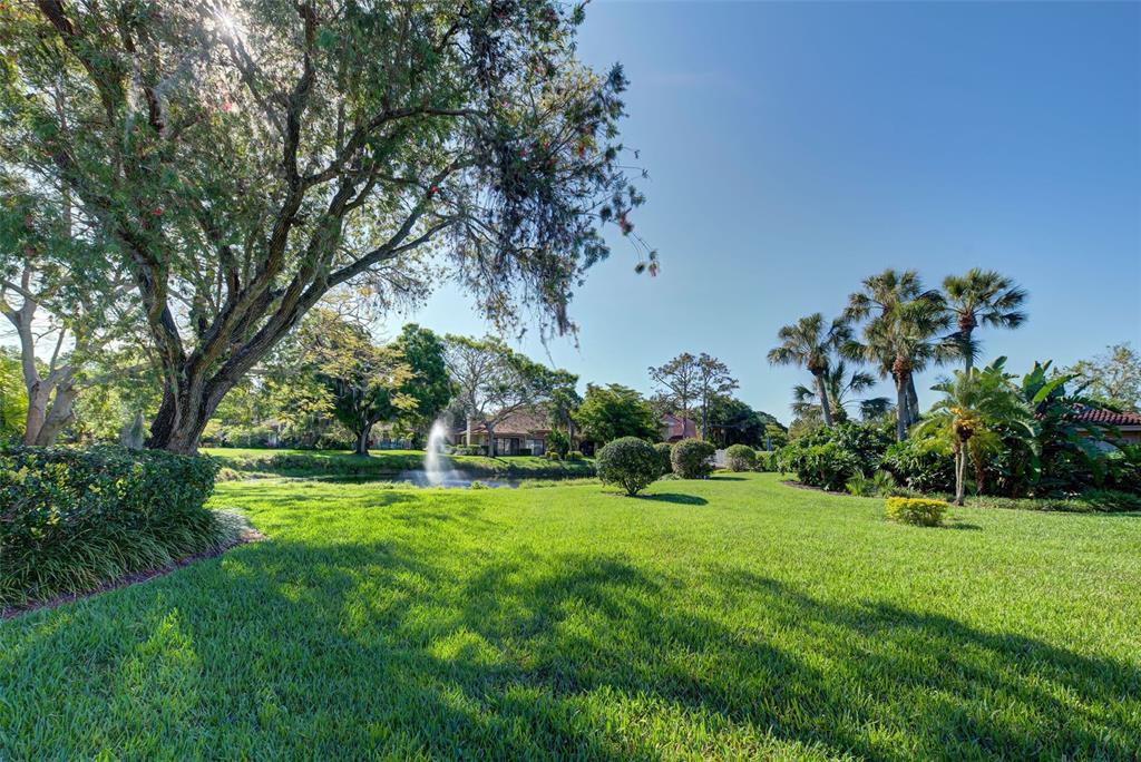 A grassy lawn leads to a small pond with a fountain and surrounding trees — 1740 LANDINGS BOULEVARD UNIT 39, SARASOTA, FL