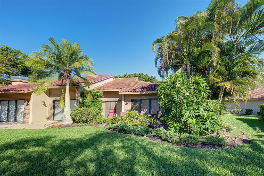 The exterior of a tan house features a tiled roof, palm trees, and a grassy lawn — 1740 LANDINGS BOULEVARD UNIT 39, SARASOTA, FL