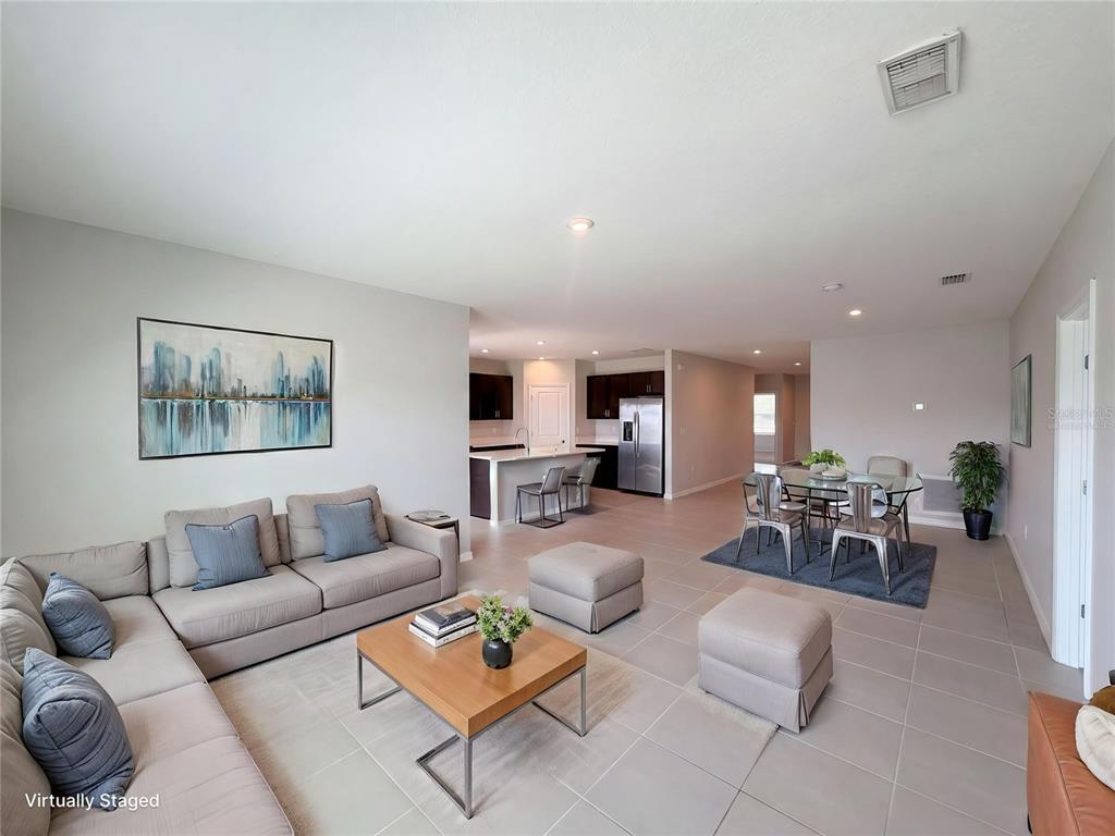 An open-concept living and dining area features tile flooring, a sectional sofa, and kitchen island — 221 AQUAMARINE LANE, KISSIMMEE, FL