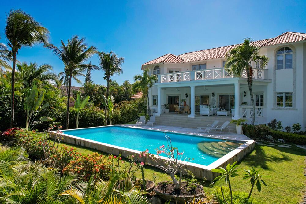 A two-story white house with a swimming pool, patio, and lush tropical landscaping — 123 Villa Cabarete, FL