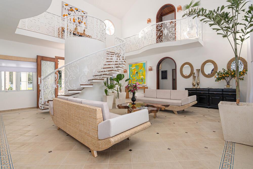 A spacious living room features a white spiral staircase, tiled floors, and modern wicker furniture — 123 Villa Cabarete, FL
