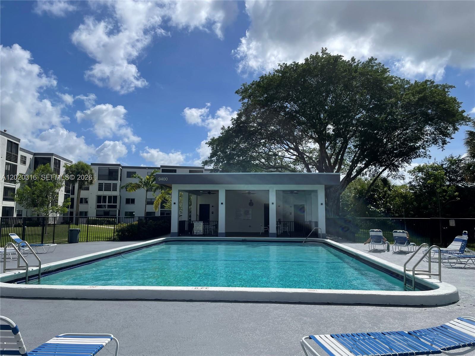 An outdoor swimming pool is surrounded by a concrete deck, lounge chairs, and a pavilion — 9235 SW 8th St # 209, Boca Raton FL 33428, BOCA RATON, FL
