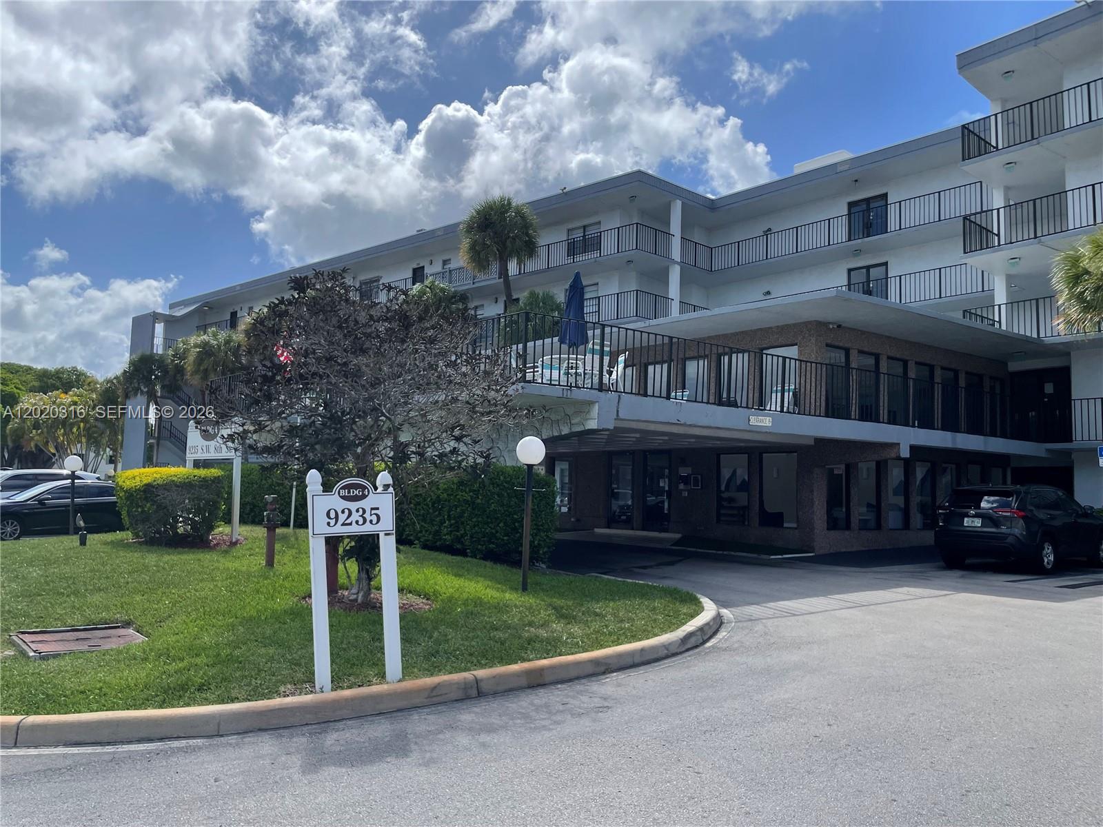 A multi-story apartment building with a covered entrance and a parking area in front — 9235 SW 8th St # 209, Boca Raton FL 33428, BOCA RATON, FL