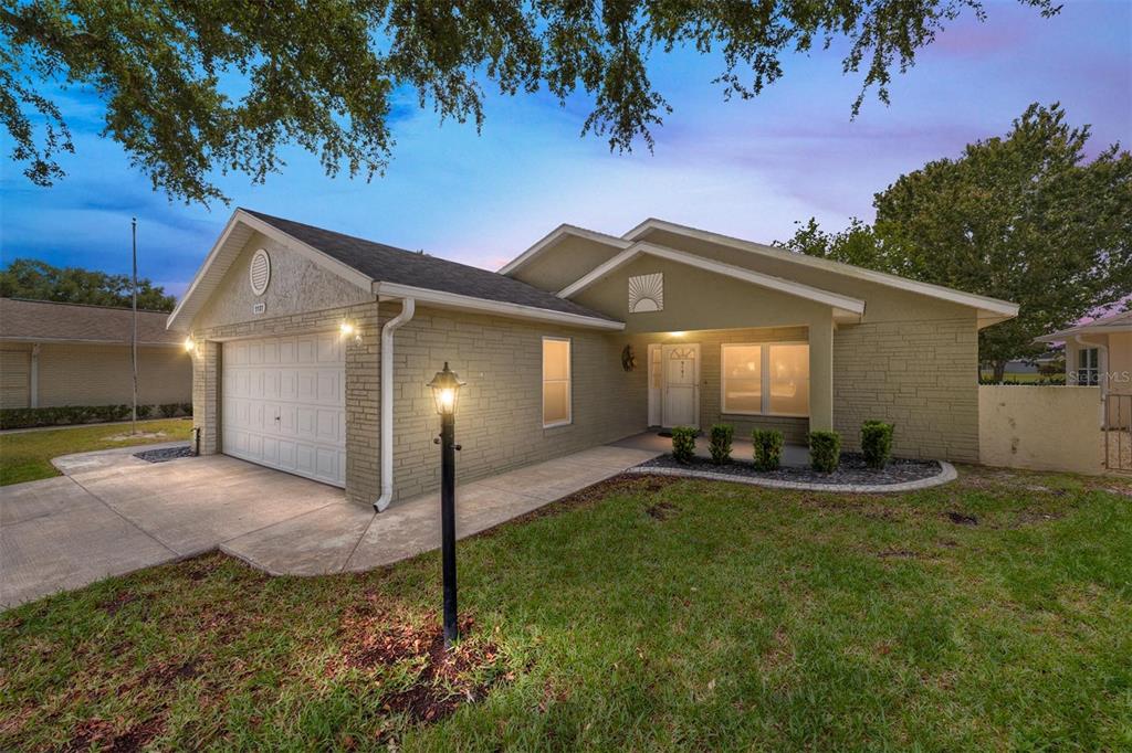 A single-story house with a tan brick facade, a two-car garage, and a front lawn — 9181 SW 91ST CIRCLE, OCALA, FL