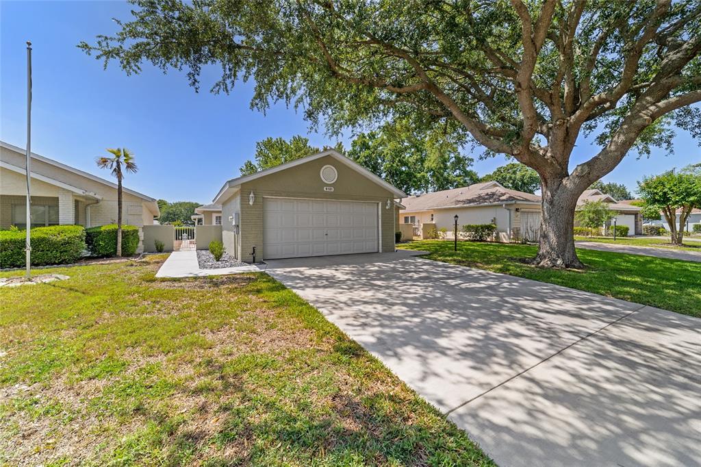 A single-story house with a two-car garage, a concrete driveway, and a large oak tree — 9181 SW 91ST CIRCLE, OCALA, FL