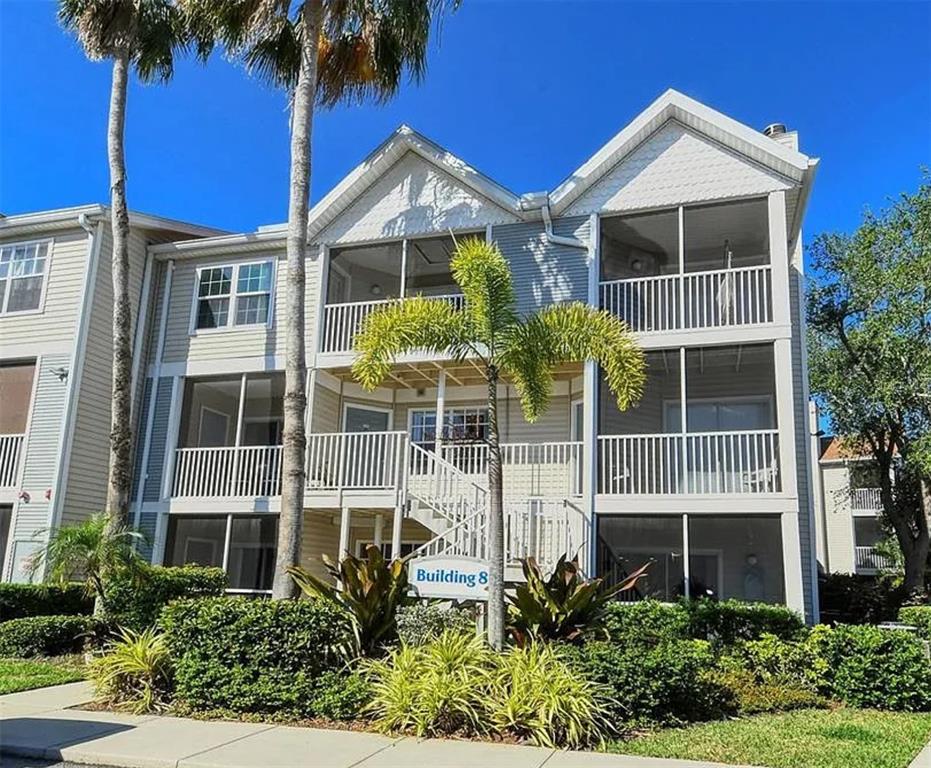 A three-story apartment building with screened balconies and a palm tree in the front yard — 850 S TAMIAMI TRAIL UNIT 801, SARASOTA, FL