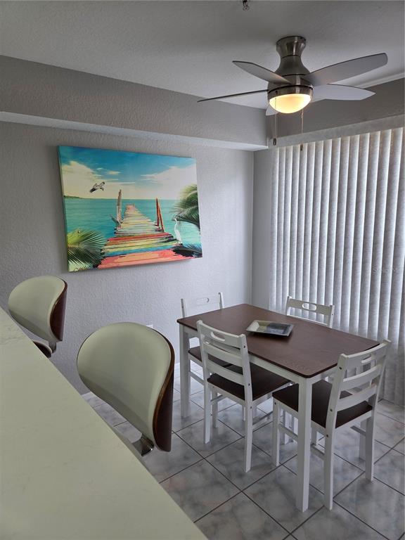 A dining area features a wooden table with four white chairs beneath a ceiling fan — 850 S TAMIAMI TRAIL UNIT 801, SARASOTA, FL