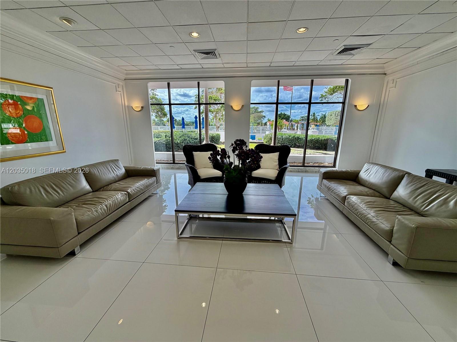 A bright lobby features white marble floors, a glass-topped table, and two hanging pendant lights — 5700 Collins Ave # 14M, Miami Beach FL 33140, MIAMI BEACH, FL