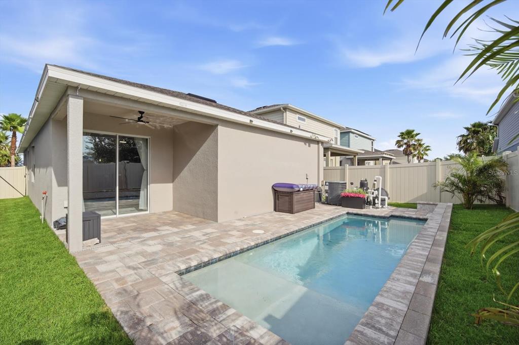 A backyard features a small rectangular swimming pool, a paved patio, and a covered porch — 12261 BLUE PACIFIC DRIVE, RIVERVIEW, FL