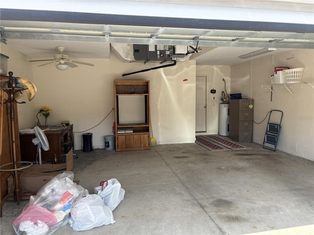 A garage with a concrete floor, a ceiling fan, an HVAC unit, and storage furniture — 420 GLEN ARBOR LANE, LEESBURG, FL