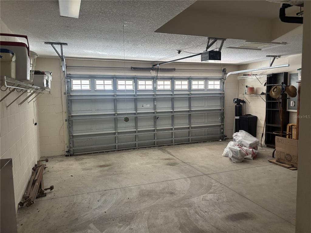 A two-car garage with a sectional door, concrete floor, and wall-mounted storage shelving — 420 GLEN ARBOR LANE, LEESBURG, FL
