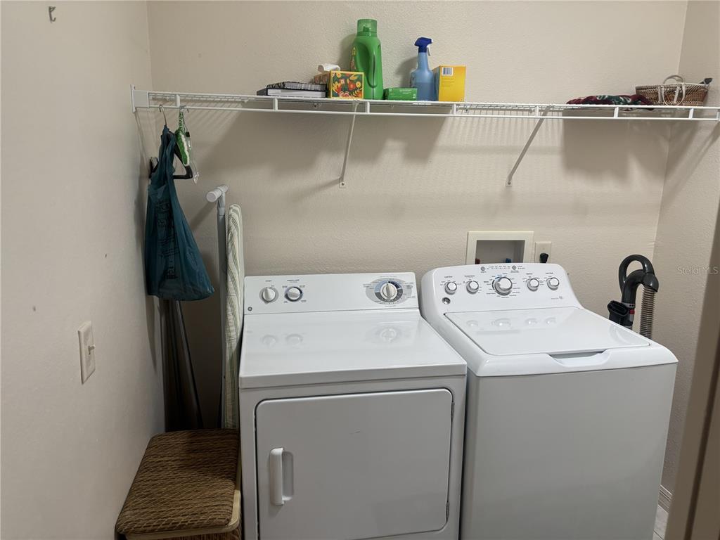 A laundry room features a white washer and dryer, a wire shelf, and a small stool — 420 GLEN ARBOR LANE, LEESBURG, FL