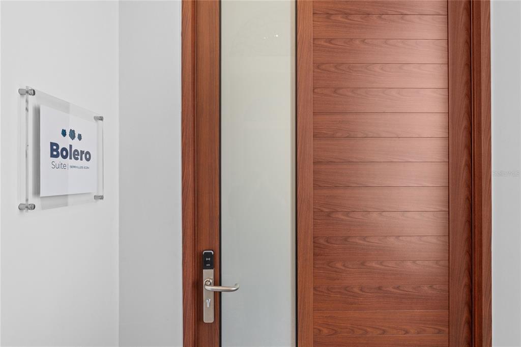 A modern wooden door with a glass panel stands next to a Bolero Suite sign — 6951 C REINA ISABEL STE. 101 UNIT 3B Bolero, PONCE, PR