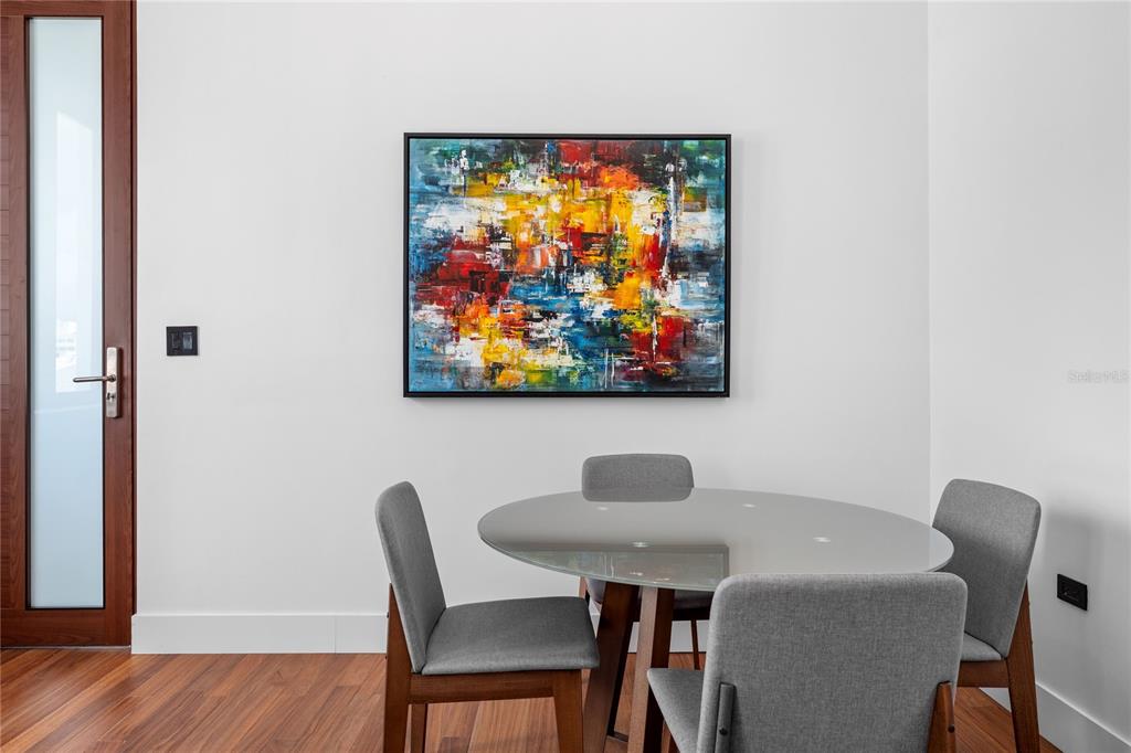 A dining area features a round glass table, four gray chairs, and abstract wall art — 6951 C REINA ISABEL STE. 101 UNIT 3B Bolero, PONCE, PR