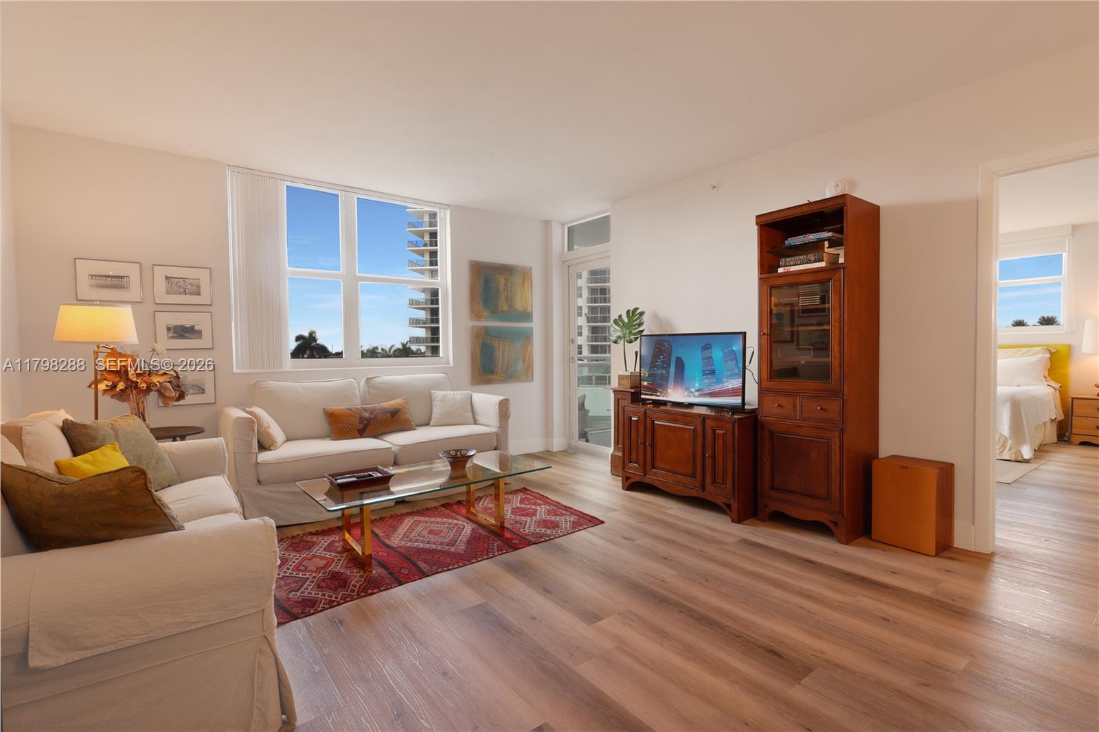 A living room features a white sofa, a glass coffee table, and wood-look flooring — 3001 S Ocean Dr # 443, Hollywood FL 33019, HOLLYWOOD, FL