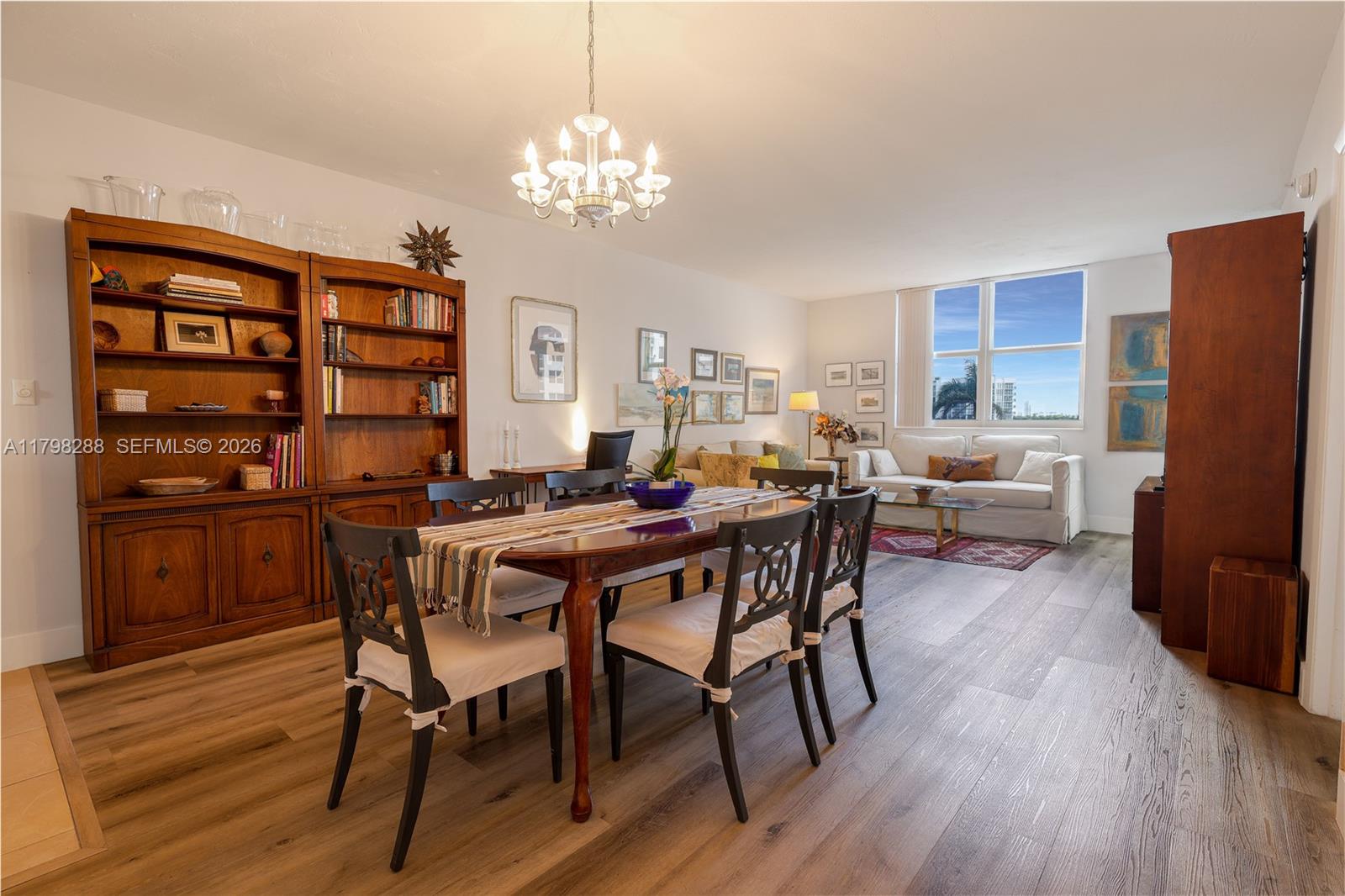 A dining area and living room feature wood flooring, a wooden bookshelf, and large windows — 3001 S Ocean Dr # 443, Hollywood FL 33019, HOLLYWOOD, FL