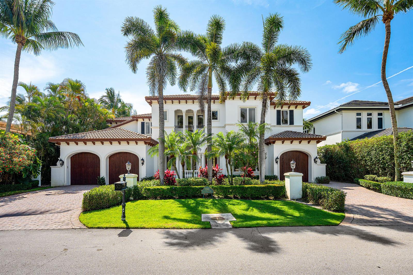 A two-story white stucco house features a tile roof, arched garage doors, and palm trees — 1282 Sabal Palm Drive, Boca Raton FL 33432, BOCA RATON, FL