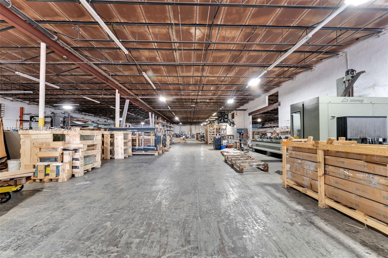 A large industrial warehouse interior features concrete floors, exposed ceiling trusses, and stacked wooden crates — 315 W 75th Pl, Hialeah FL 33014, HIALEAH, FL