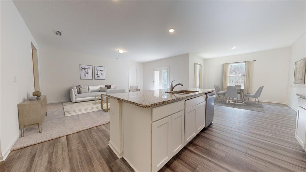An open-concept kitchen with a granite island overlooks a living room and dining area — 13256 BENDING CREEK TRAIL, PARRISH, FL