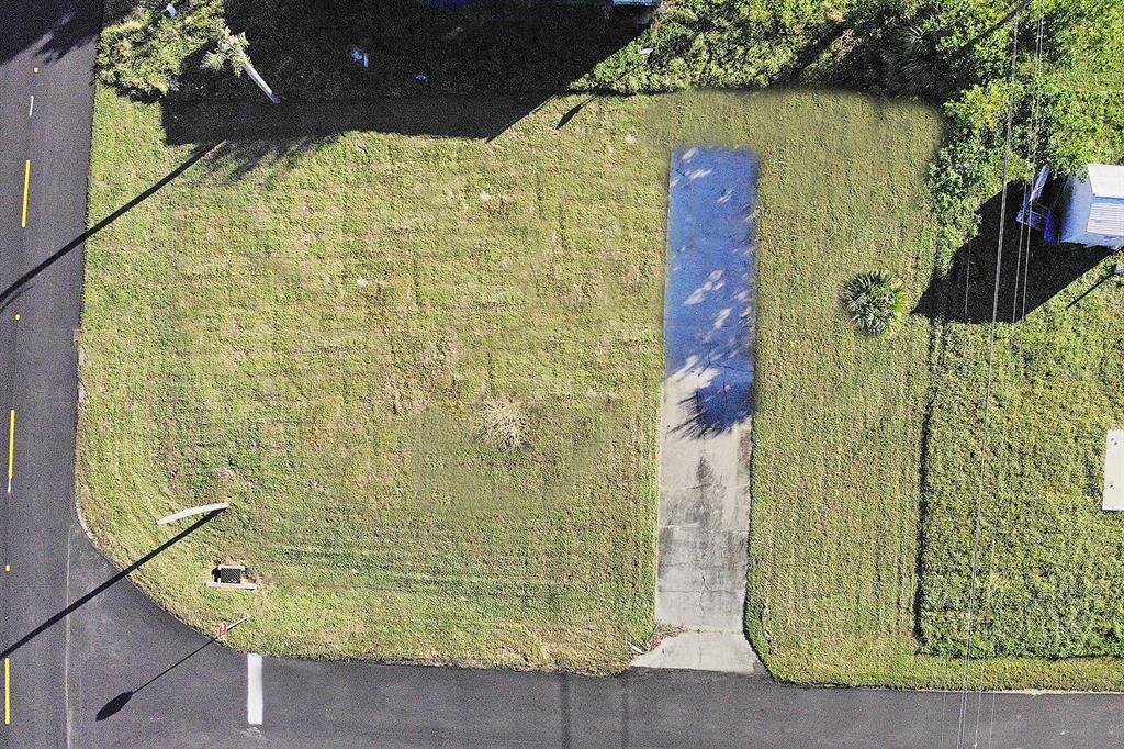 An aerial view shows a rectangular grassy lot with a concrete driveway and street access — 1384 FLAMINGO DRIVE, ENGLEWOOD, FL