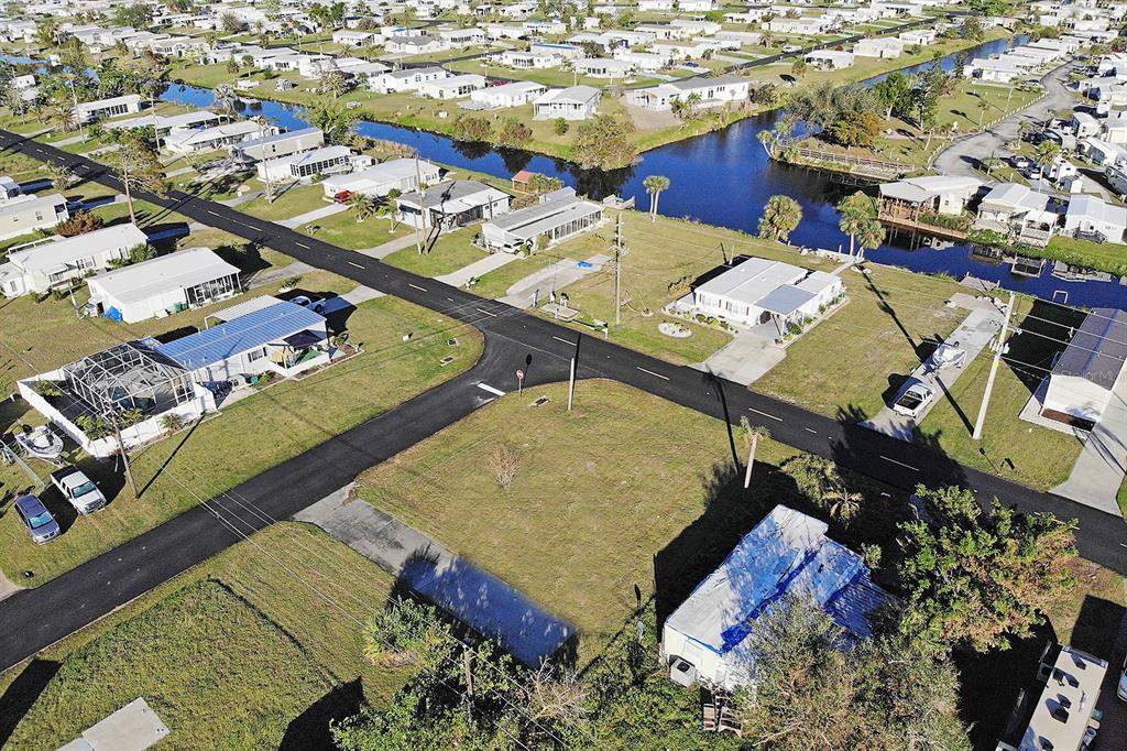 An aerial view shows a vacant residential lot situated at a street intersection near a canal — 1384 FLAMINGO DRIVE, ENGLEWOOD, FL