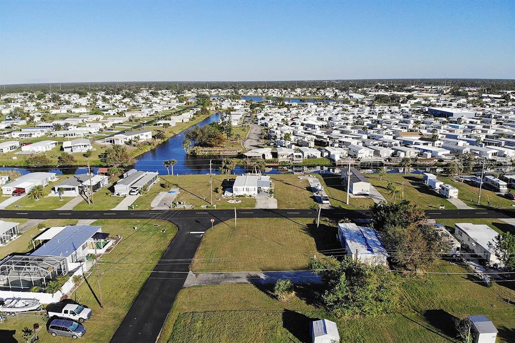 An aerial view shows a residential neighborhood with mobile homes, a canal, and vacant lots — 1384 FLAMINGO DRIVE, ENGLEWOOD, FL