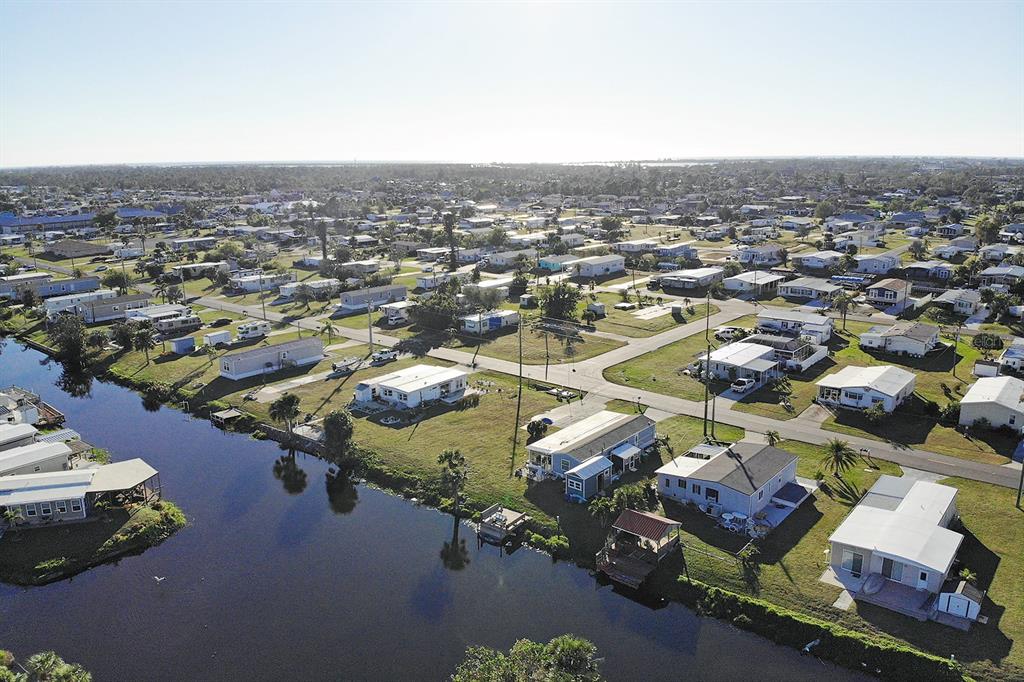 An aerial view shows a residential neighborhood of manufactured homes situated along a canal — 1384 FLAMINGO DRIVE, ENGLEWOOD, FL