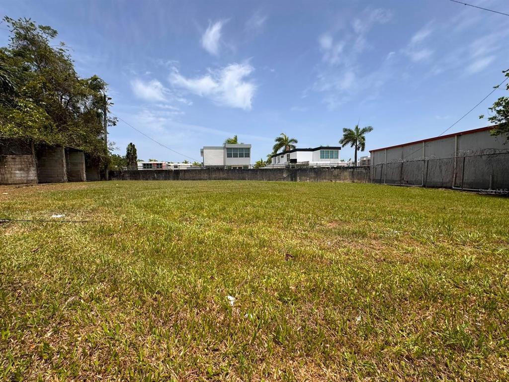 A flat, grassy vacant lot enclosed by a concrete wall and chain-link fencing — Carr 738 KM 1.4 BO MONTELLANO, CAYEY, PR