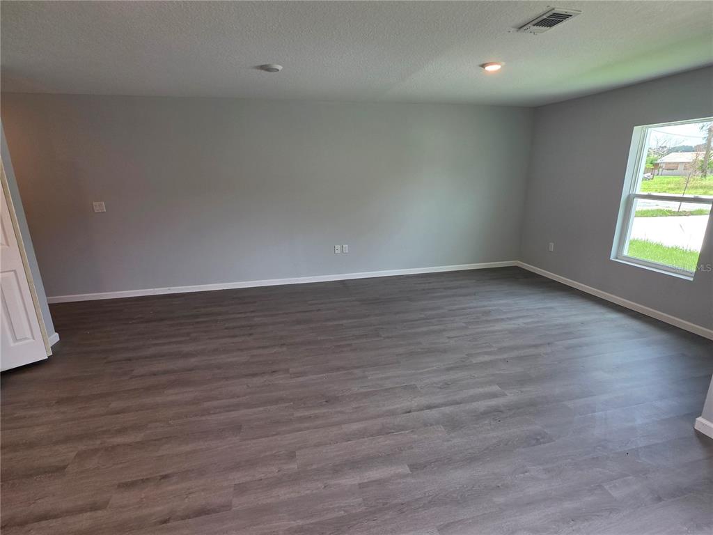 An empty room features gray walls, dark wood-look flooring, and a single window — 139 B STREET, LAKE WALES, FL