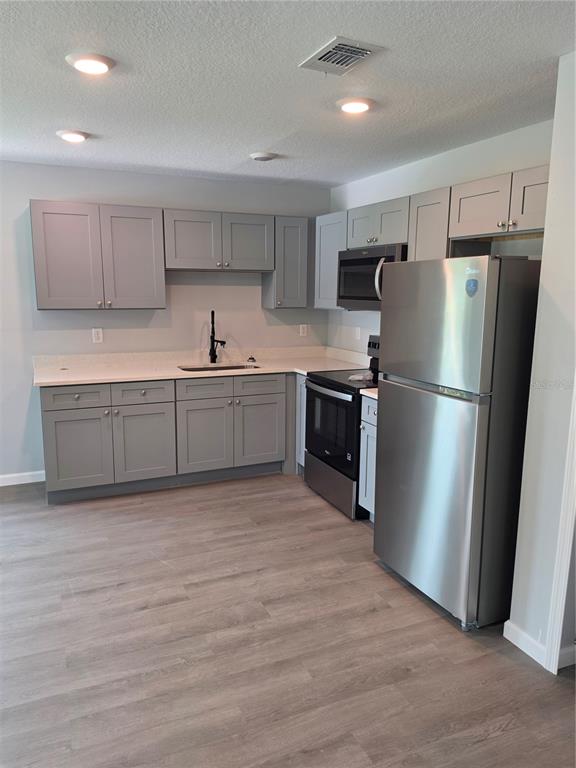 A kitchen features gray shaker cabinets, stainless steel appliances, and light-colored countertops — 139 B STREET, LAKE WALES, FL