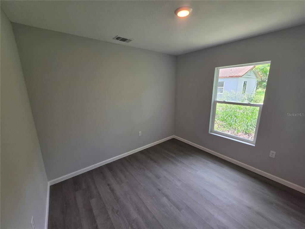 An empty bedroom features gray walls, wood-look flooring, a single window, and a ceiling light — 139 B STREET, LAKE WALES, FL