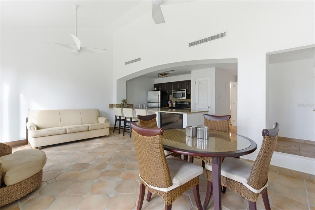 An open-concept living and dining area features tile flooring, a beige sofa, and kitchen access — Las Casitas I 1000 AVENUE EL CONQUISTADOR UNIT 5214-15-16, FAJARDO, PR