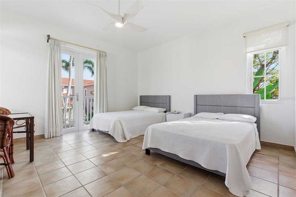 A bedroom with two beds, tile flooring, a ceiling fan, and a balcony door — Las Casitas I 1000 AVENUE EL CONQUISTADOR UNIT 5214-15-16, FAJARDO, PR