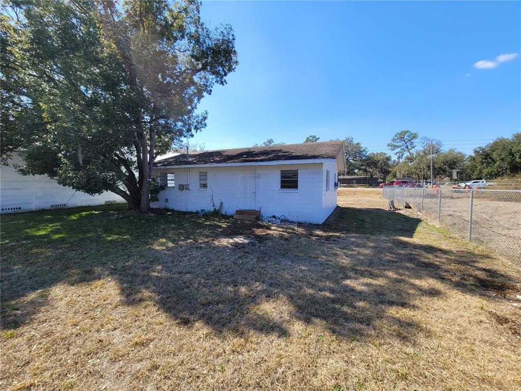 A white, single-story house with a shingled roof stands on a dry, grassy lot — 4830 GALL BOULEVARD, ZEPHYRHILLS, FL