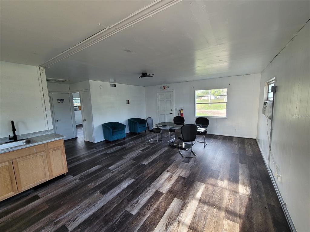 A room with wood-look flooring, a small kitchenette, a dining table, and two armchairs — 4830 GALL BOULEVARD, ZEPHYRHILLS, FL