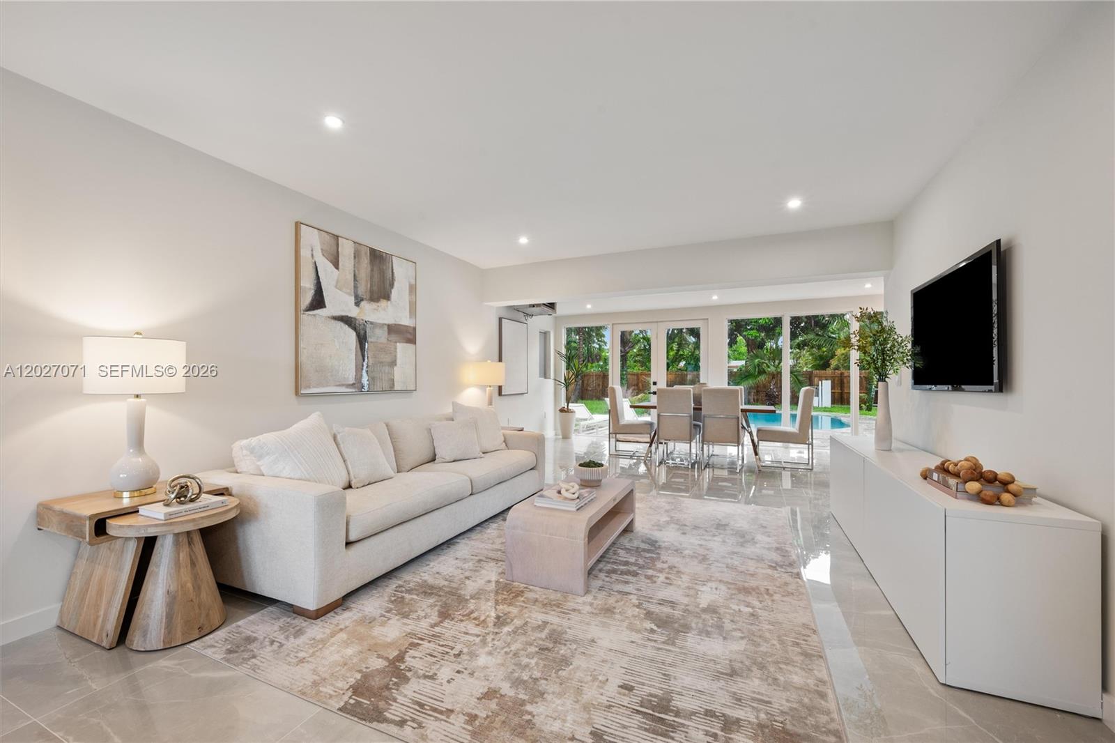 A bright living room features a beige sofa, area rug, and a view of a pool — 4024 Monroe St, Hollywood FL 33021, HOLLYWOOD, FL