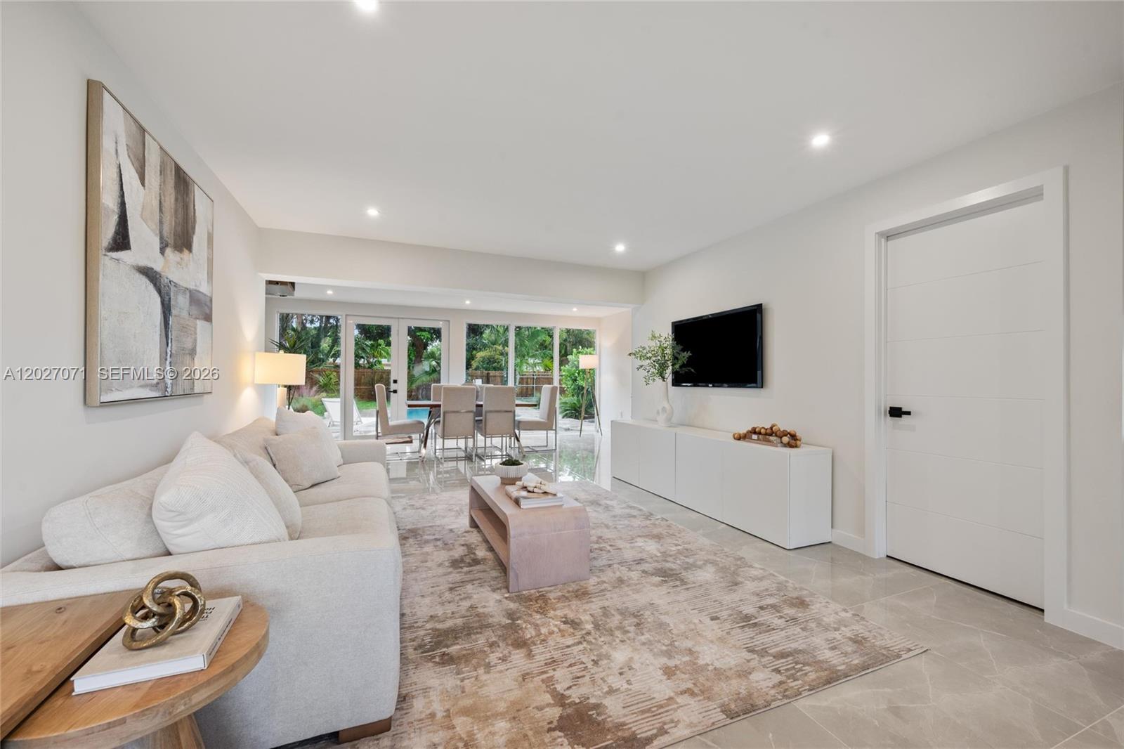 A living room features a white sofa, a modern coffee table, and a wall-mounted television — 4024 Monroe St, Hollywood FL 33021, HOLLYWOOD, FL