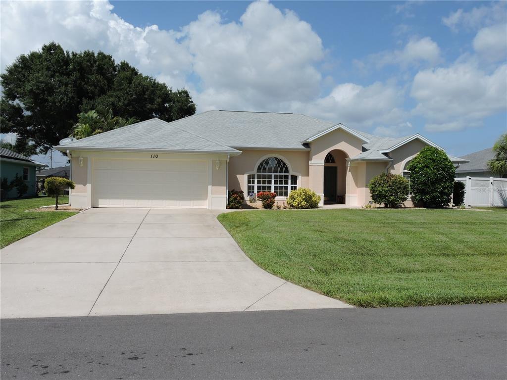 A single-story house with a beige stucco exterior, a two-car garage, and a front lawn — 110 MARINER LANE, ROTONDA WEST, FL