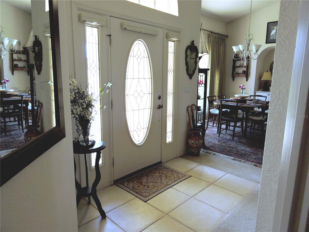 An entryway with tile flooring, a white front door, and an adjacent dining area — 110 MARINER LANE, ROTONDA WEST, FL