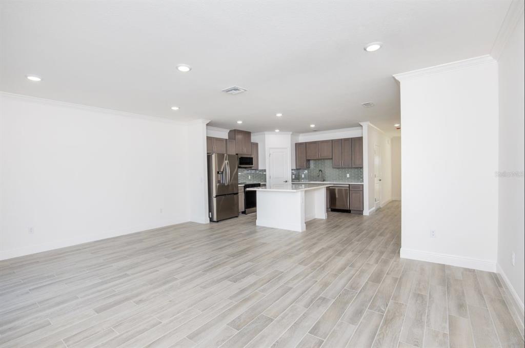 An open-concept kitchen with dark wood cabinets, stainless steel appliances, and light wood-look flooring — 10536 FOUNTAIN PALM CIRCLE, BOKEELIA, FL