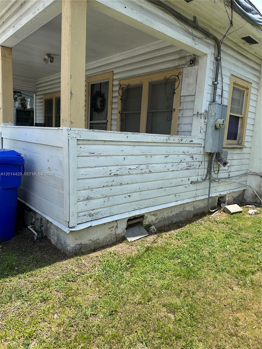 The exterior of a house features a covered porch with peeling white wood siding — 3566 Thomas Ave, Miami FL 33133, MIAMI, FL