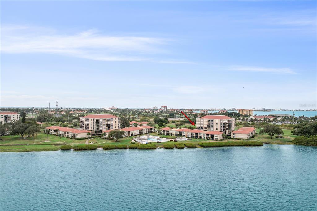 An aerial view of a waterfront apartment complex with a swimming pool and red roofs — 6104 PALMA DEL MAR BOULEVARD S UNIT 302, ST PETERSBURG, FL