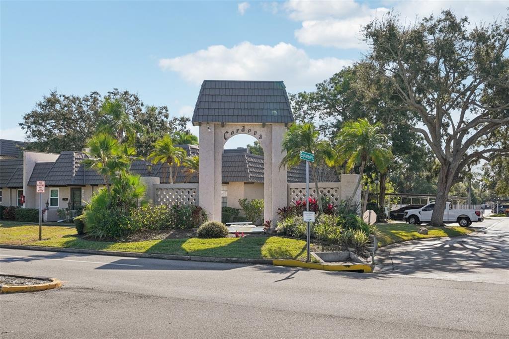 A stone archway entrance with the name Cordova stands before residential buildings and landscaping — 404 CORDOVA GREEN UNIT 404, SEMINOLE, FL