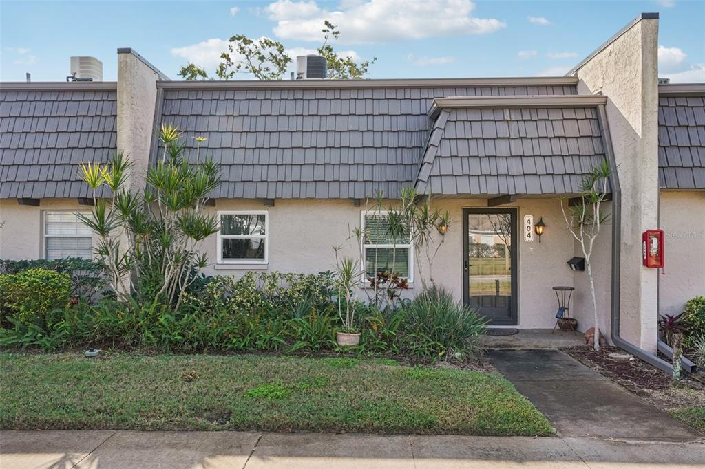 The exterior of a single-story townhouse features a gray mansard roof and a front entrance — 404 CORDOVA GREEN UNIT 404, SEMINOLE, FL
