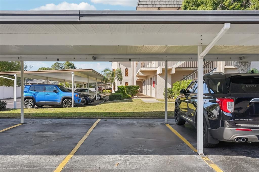 A covered parking area features several numbered spaces with cars parked underneath — 404 CORDOVA GREEN UNIT 404, SEMINOLE, FL