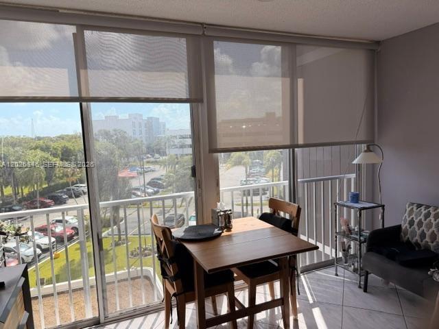 A dining area with a wooden table and chairs sits beside a balcony with blinds — 3850 Washington St # 409, Hollywood FL 33021, HOLLYWOOD, FL