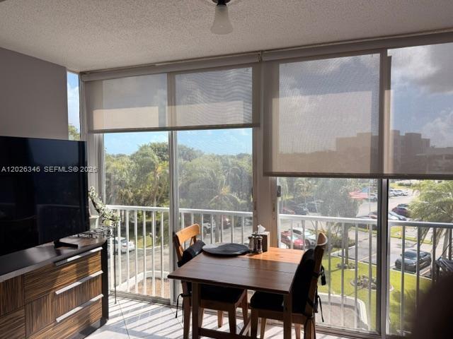 A dining area with a wooden table and chairs sits before large windows overlooking trees — 3850 Washington St # 409, Hollywood FL 33021, HOLLYWOOD, FL