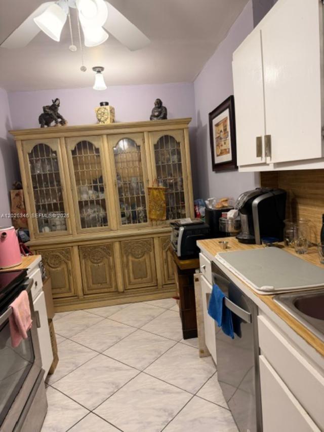A kitchen features white cabinets, a large wooden hutch, and light-colored tile flooring — 3850 Washington St # 409, Hollywood FL 33021, HOLLYWOOD, FL